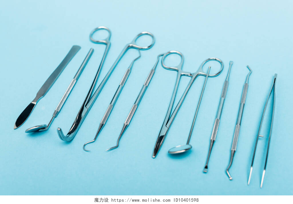 蓝色桌子上的一堆牙医工具蓝色背景下一排牙齿工具的近景